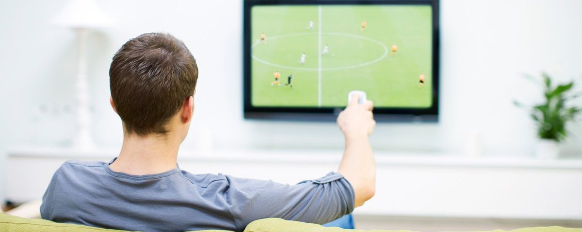 Homem assistindo futebol na televisão.