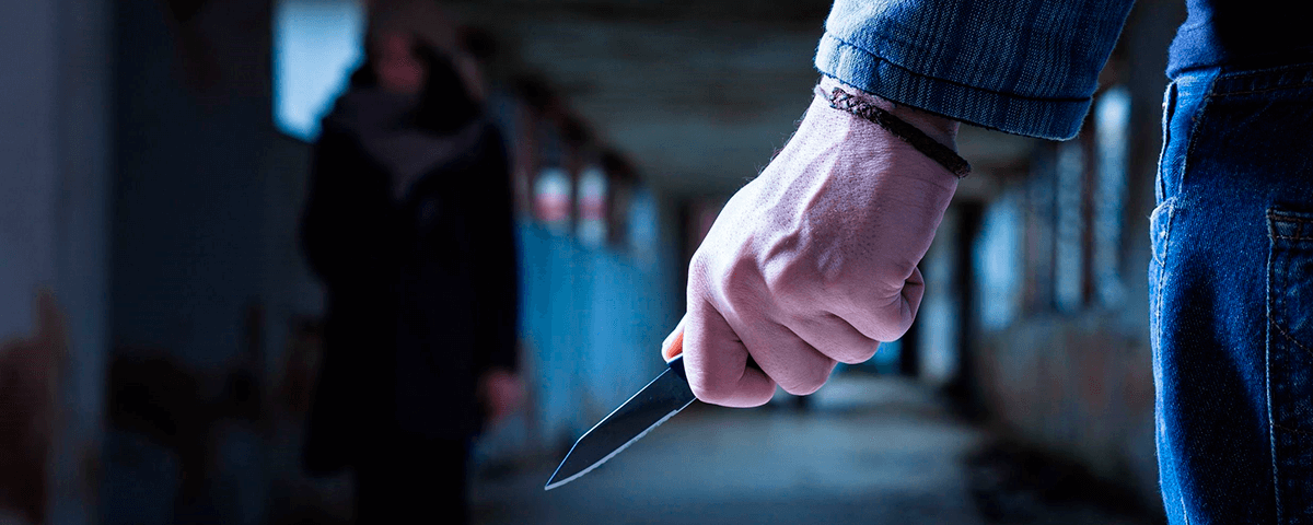 Homem com faca na mão à espera da vítima que caminha por perto.