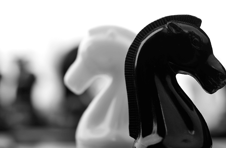 Cavalos de xadrez, preto e branco, de costas um para o outro.